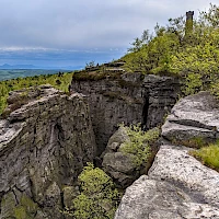 Felsenwand an der Südseite des Berges mit dem Felsmassiv 'Hundewand' (Psí stěna) und dem Aussichtsturm (© Norbert Kaiser; Wikipedia; CC BY-SA 4.0)